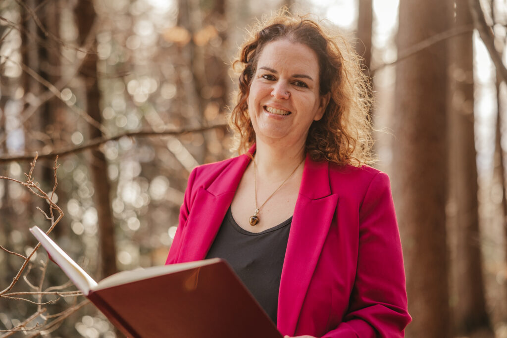 Portrait Alexandra Baumann im roten Blazer im Wald